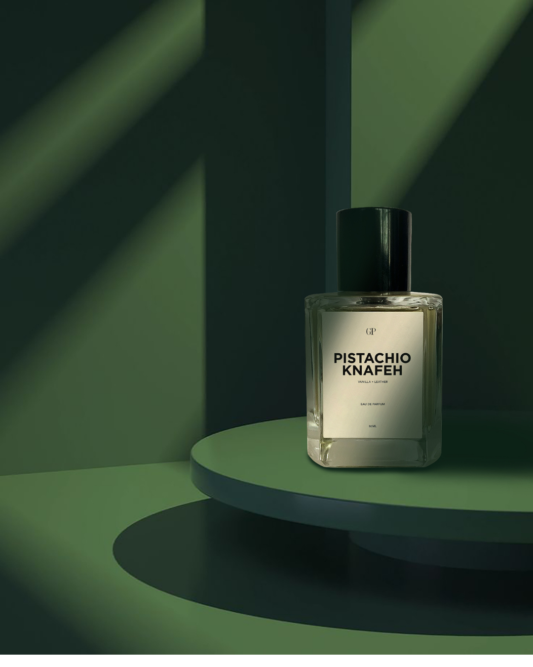 A clear glass perfume bottle with a black cap and a white label reading 'PISTACHIO KNAFEH' by the brand 'UP', set on a green tiered platform with dramatic green shadows.